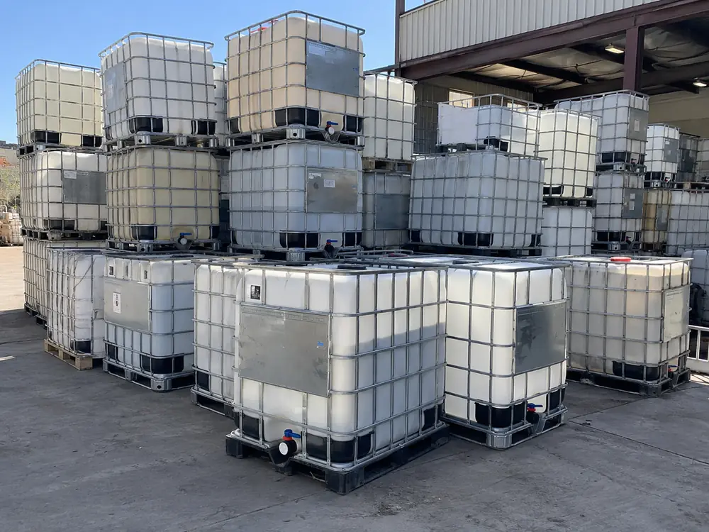Composite IBC totes stacked in the yard, the format stainless replaces for aggressive service
